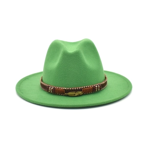 Detail of green fedora hat featuring woven brown band and golden metal feather pendant