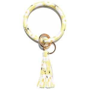 Detail view of yellow leather bracelet keychain with daisy pattern and fringe tassel