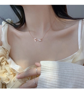 Close-up of rose gold tulip pendant necklace with opal gemstone on a female neck