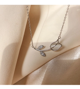 Macro shot of a silver tulip necklace with pearl petal and zircon leaves on beige satin