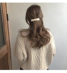Detail of 8.5cm cream acetate hair clip worn on long wavy hair with a marble texture