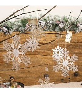 Detailed view of glittering silver and gold snowflake ornaments hanging on rustic branches