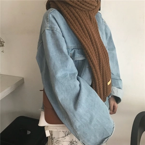 Detail of chunky brown knit scarf with vertical texture paired with denim jacket
