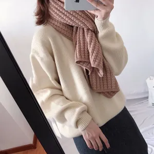 Detail of chunky knit scarf in dusty rose color paired with cream sweater