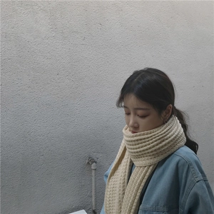 Detail showing beige chunky knit scarf texture with thick ribbed pattern for winter