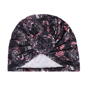 Macro view of paisley print turban hat with large twisted rose floral knot detail