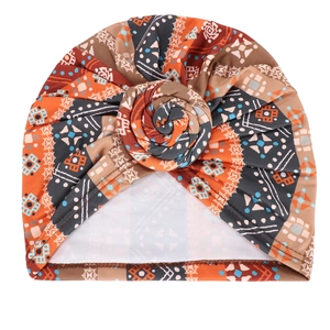 Detail of bohemian geometric print turban hat with orange and brown twist knot design