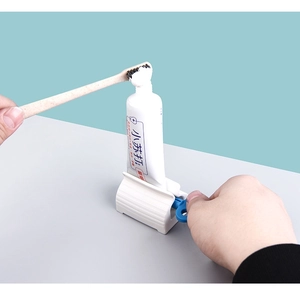 Detail of manual toothpaste squeezer with blue handle showing rolling action