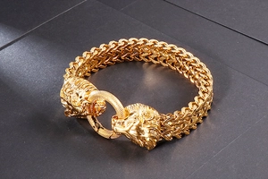 Detailed macro view of golden lion head clasps and woven chain on a steel bracelet