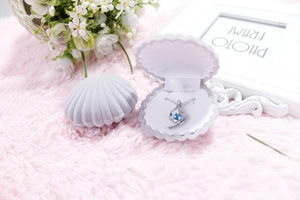 Macro shot of a purple shell-shaped velvet jewelry box featuring a blue gemstone necklace
