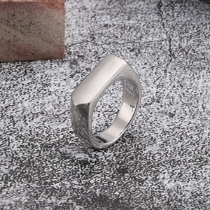 Close-up of a silver geometric stainless steel signet ring on a grey industrial stone