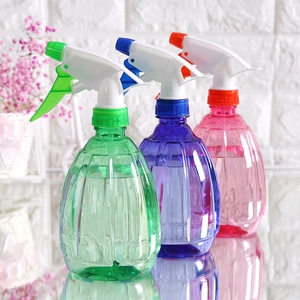 Three candy-colored transparent plastic garden spray bottles in green, blue, and pink