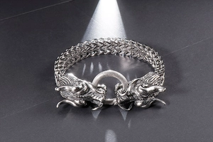 Detailed view of polished stainless steel double dragon head clasp on heavy woven bracelet