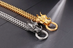 Detailed view of silver and gold dragon head clasps with textured woven chain links
