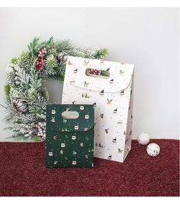 Detailed view of festive Christmas paper gift bags with die-cut handles and holiday patterns