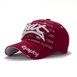 Detailed close-up of distressed embroidery and vintage worn fabric on wine red baseball cap