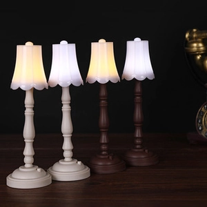 Mini vintage desk lamp keychains with warm and cool LED lights on a wooden surface