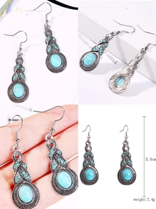 Detail view of vintage silver earrings with turquoise inlay and boho carvings