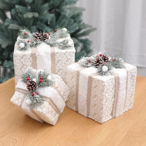 Three cream Christmas gift boxes with pine cones and berries on a wooden table setup