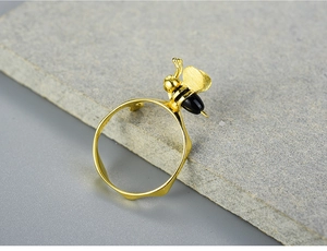 Close-up of S925 sterling silver bee ring with natural agate on grey stone texture