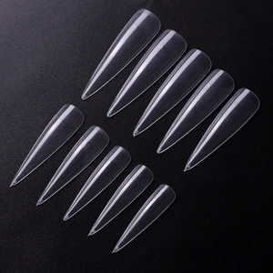 Macro detail of long stiletto clear nail tips with size numbers on textured background