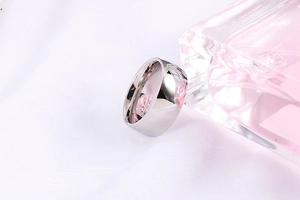 Close-up of minimalist silver stainless steel ring on white textured fabric background