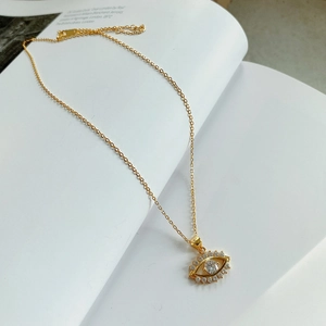 Detail of gold evil eye pendant with sparkling cubic zirconia on a minimalist chain