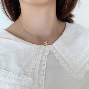 Macro shot of 925 silver evil eye pendant with pavé diamonds on a model in lace shirt