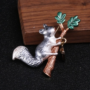 Close-up of enamel squirrel brooch with green leaves on a brown branch detail