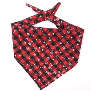 Close-up of red and black plaid dog bandana with white snowflake print and stitched edges