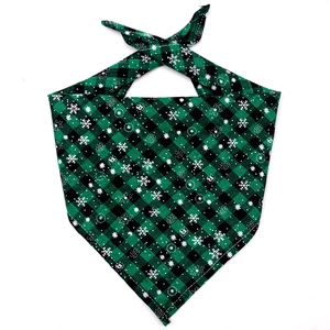 Detailed close-up of green and black plaid pet bandana with white snowflake patterns