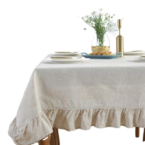 Elegant cream linen tablecloth with ruffled edges in a warm natural home setting