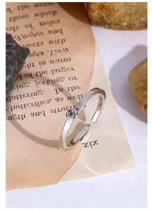 Dettaglio anello argento regolabile con diamante su sfondo di carta vintage