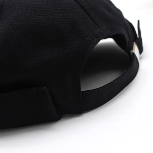 Detail of adjustable metal buckle and fabric strap on a black cotton docker brimless hat