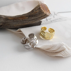Detail of irregular hammer textured wide gold and silver rings on natural fabric background