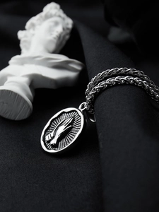 Macro shot of silver titanium steel praying hands pendant on a sleek hip hop chain