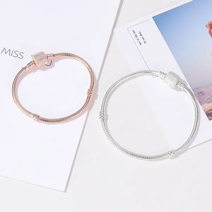 Macro shot of silver and rose gold snake chain bracelets with sparkling square crystal clasps