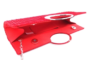Interior detail of red pleated evening bag with silver ring handle and magnetic closures