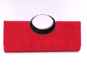 Detail of red pleated evening bag featuring a silver oval metal handle on white background