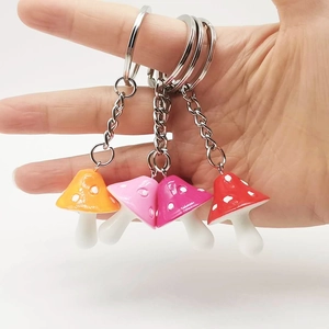 Colorful resin mushroom keychains with white dots and silver metal chains in four vibrant colors