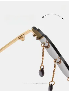 Macro detail of cloud sunglasses golden metal hinge and hanging teardrop chain charms
