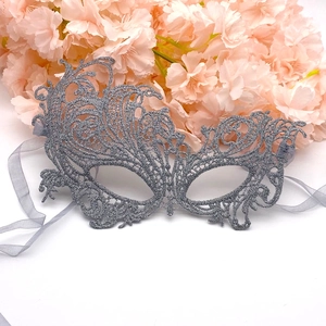 Close-up of intricate silver lace phoenix mask with floral patterns and ribbons