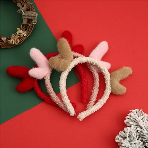 Close-up of three plush reindeer antler headbands in red, khaki, and pink festive colors