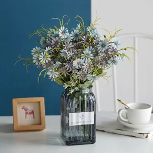 Elegant artificial grey-blue daisies in a ribbed glass vase for home decor