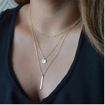 Close-up of triple-layered gold moon and star necklace with circular and bar pendants