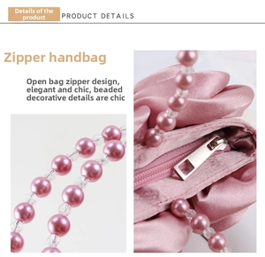 Dettaglio della borsa in raso rosa con zip in metallo e manico di perle finemente lavorate