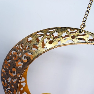 Detailed close-up of golden moon solar wind chime with intricate hollow metal patterns