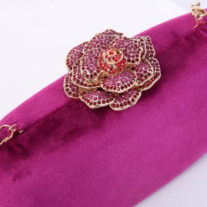 Elegant purple velvet evening clutch bag featuring a large sparkling rhinestone flower clasp