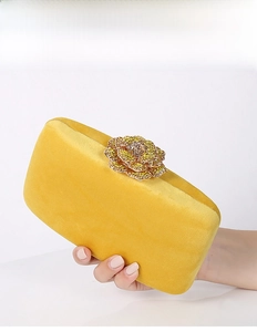 Detail of yellow velvet evening clutch bag featuring a handcrafted floral rhinestone clasp