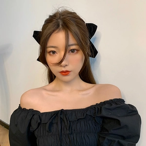 Detail showing two chic black velvet bow hair clips worn on the side by a model
